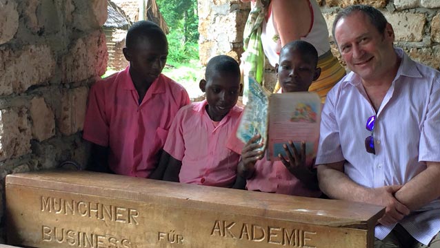 Dr. Gerhard Helm, Gründer und Geschäftsführer der Münchner Akademie für Business Coaching, beim Besuch in Kenia 2016 mit ein paar Schülern und der Schulbank, die von der Coaching-Akademie gestiftet wurde.